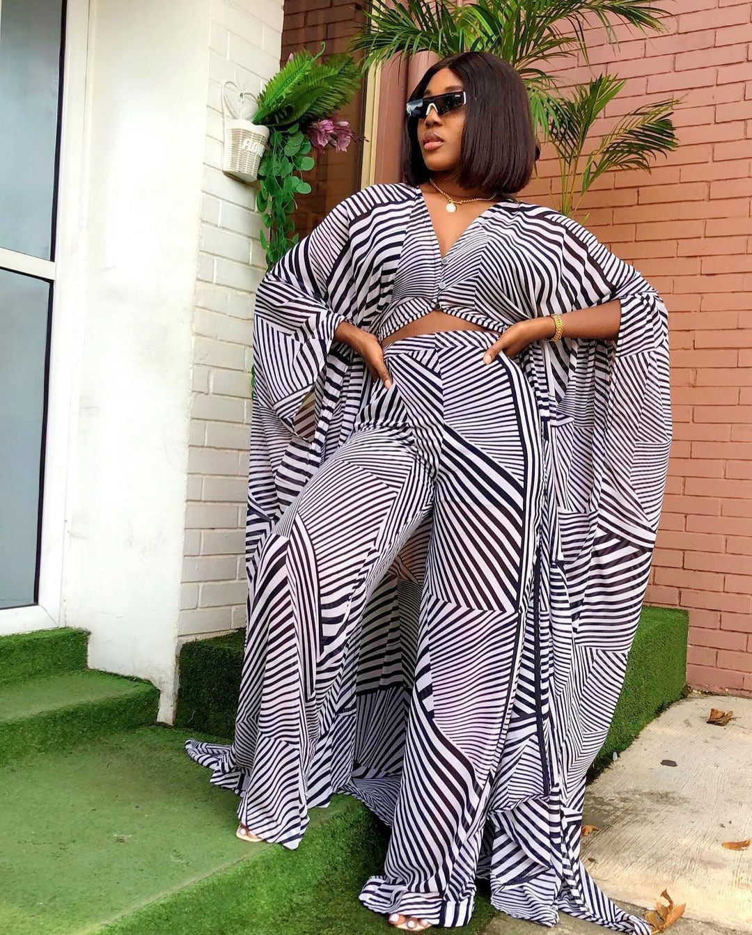 Woman wearing a black and white patterned outfit standing on a green lawn.