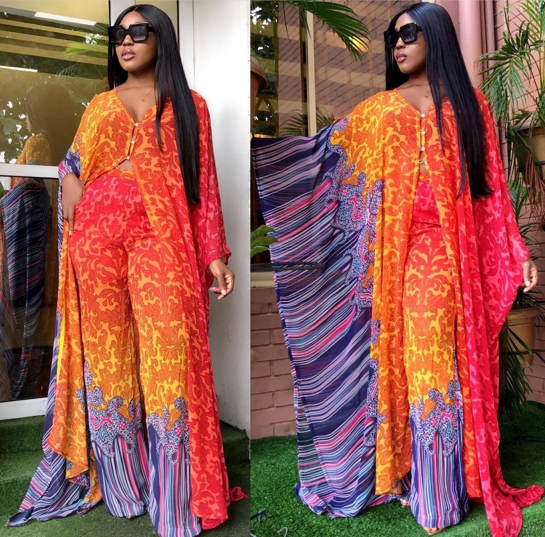 Woman wearing a colorful dress with a patterned design, standing outdoors.