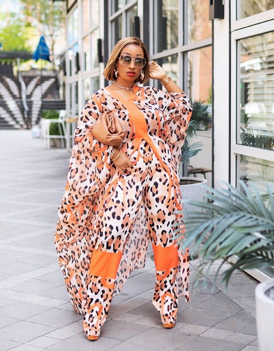 Woman wearing a leopard print outfit with orange accents in an urban setting.