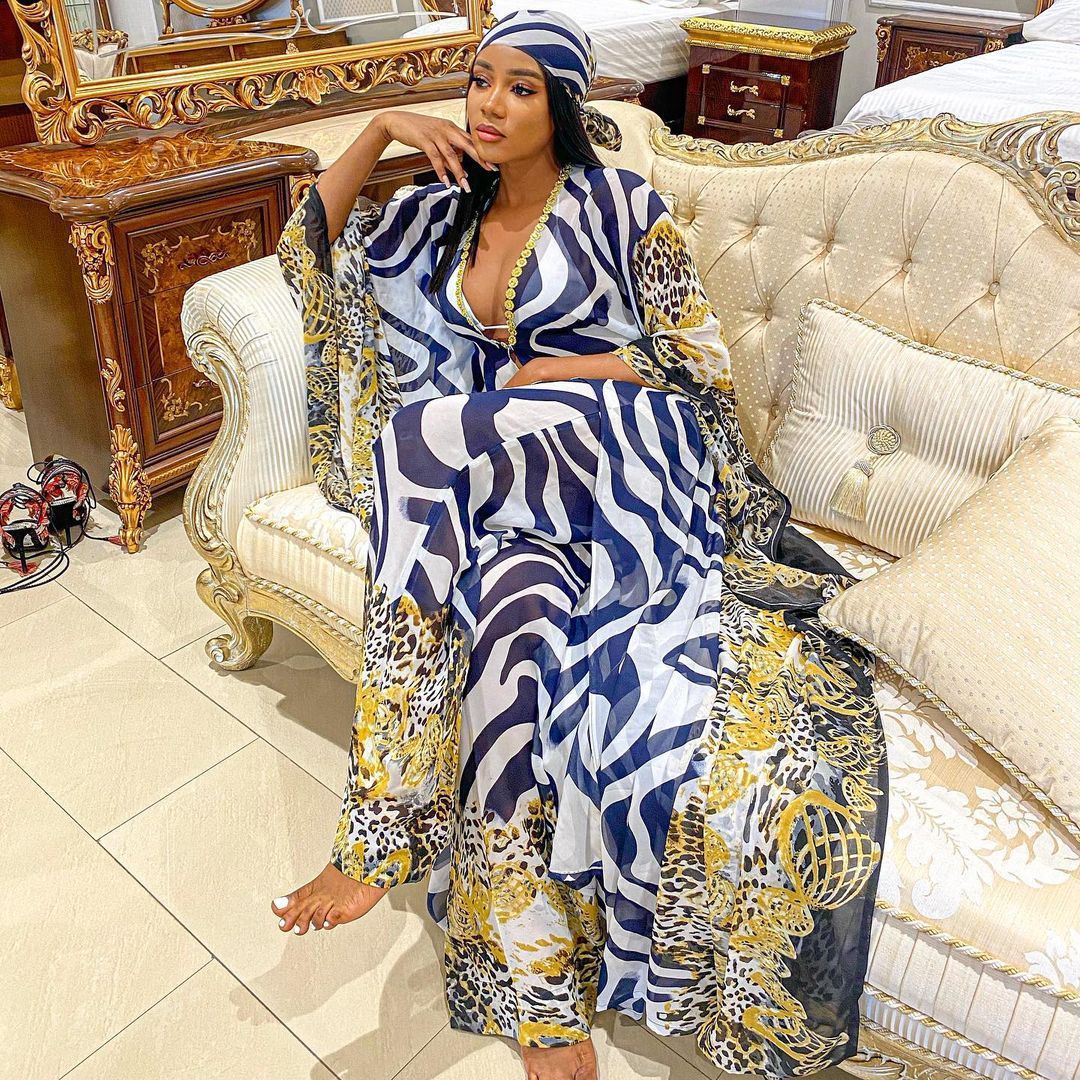 Woman in a patterned outfit sitting on an ornate couch in a luxurious room.