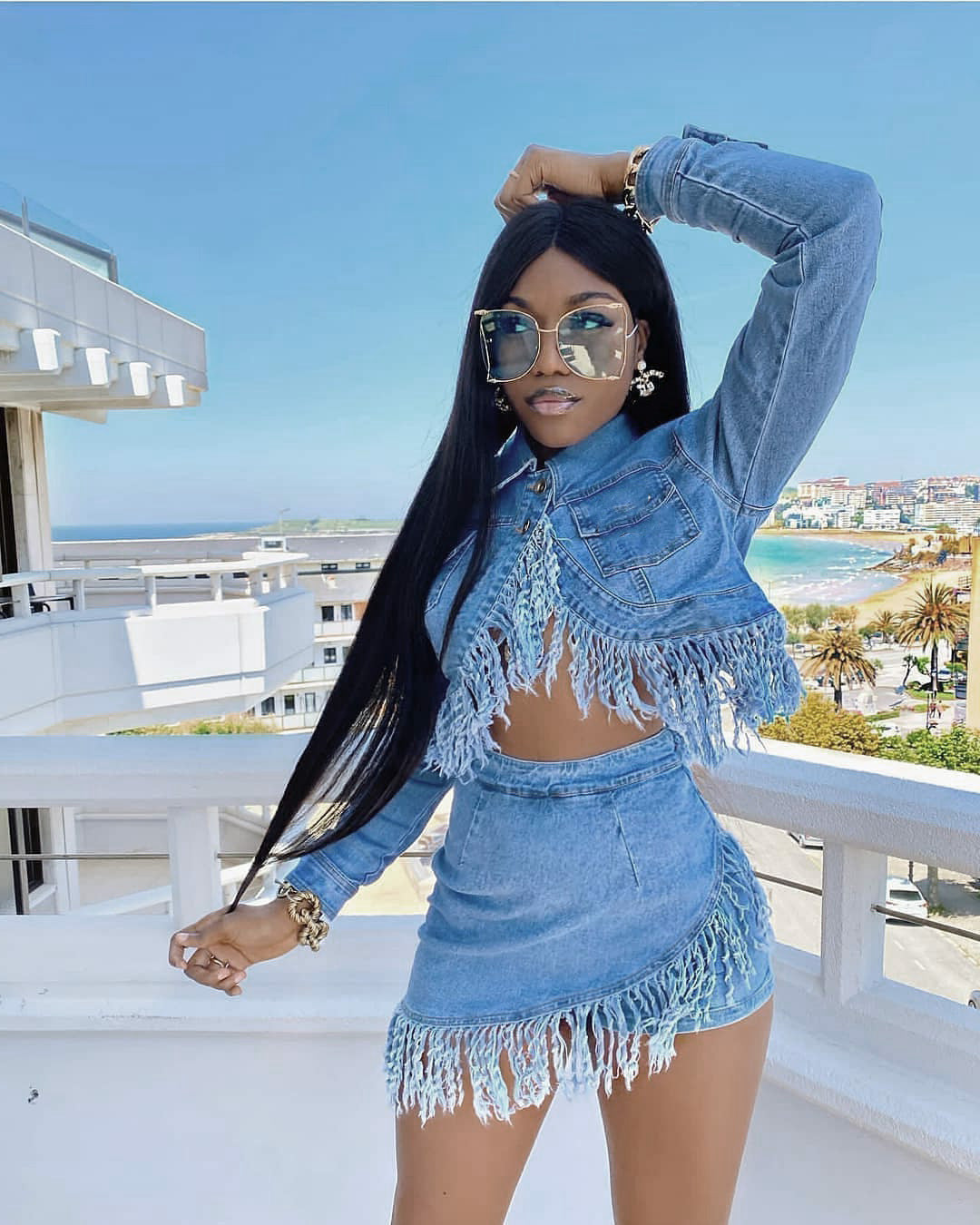 Woman in a denim outfit with fringe details on a balcony with ocean view
