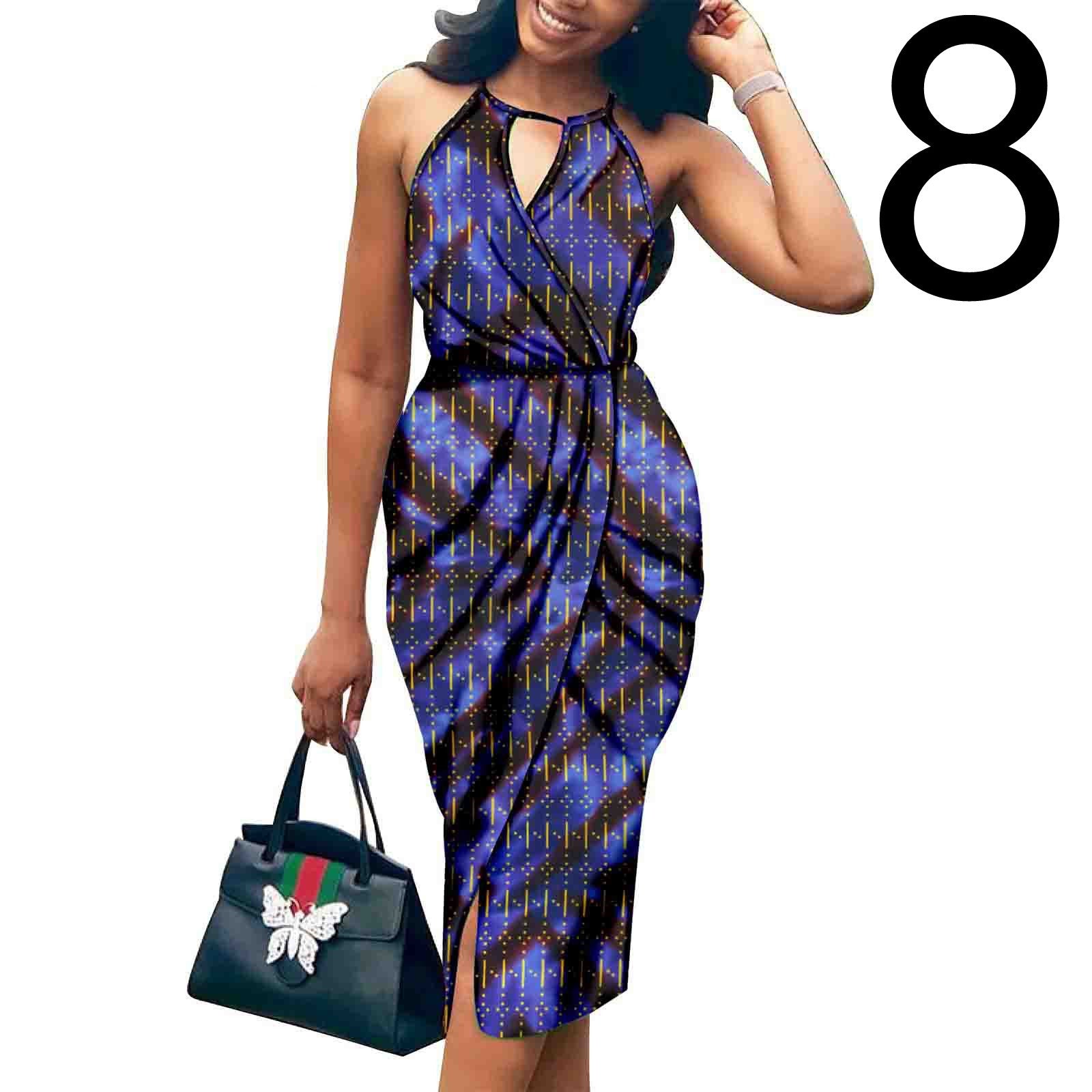 Woman wearing a blue patterned dress holding a black handbag with a visible brand logo on a white background.