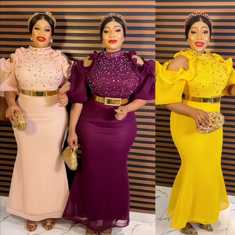 Three women in formal dresses with gold belts and clutch bags against a striped wall.