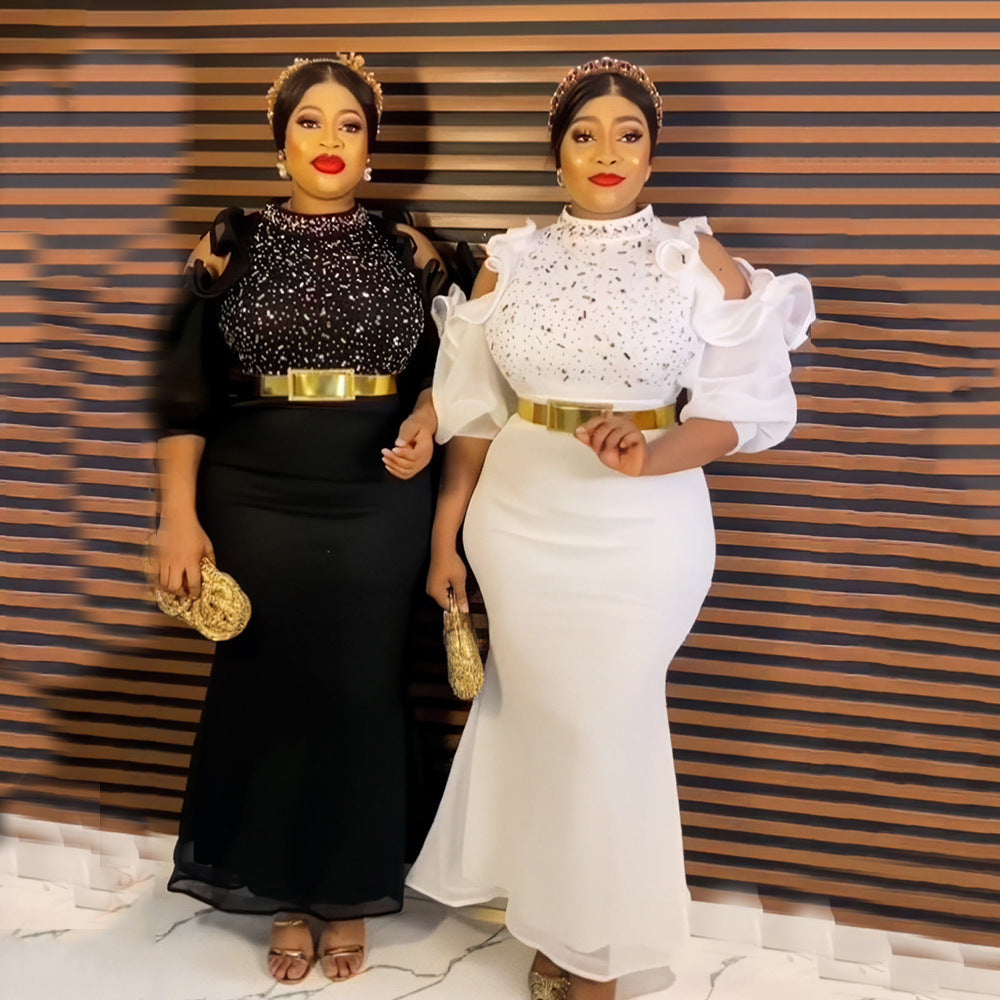 Two women in black and white formal dresses standing against a striped wall.