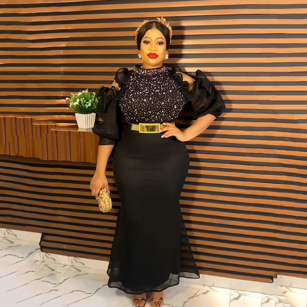 Woman in a black evening gown holding an award against a striped wall.