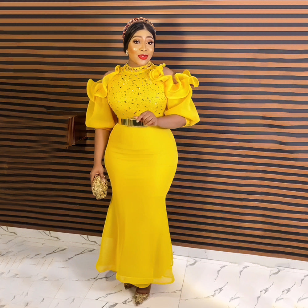 Woman in a yellow dress standing against a striped wall.