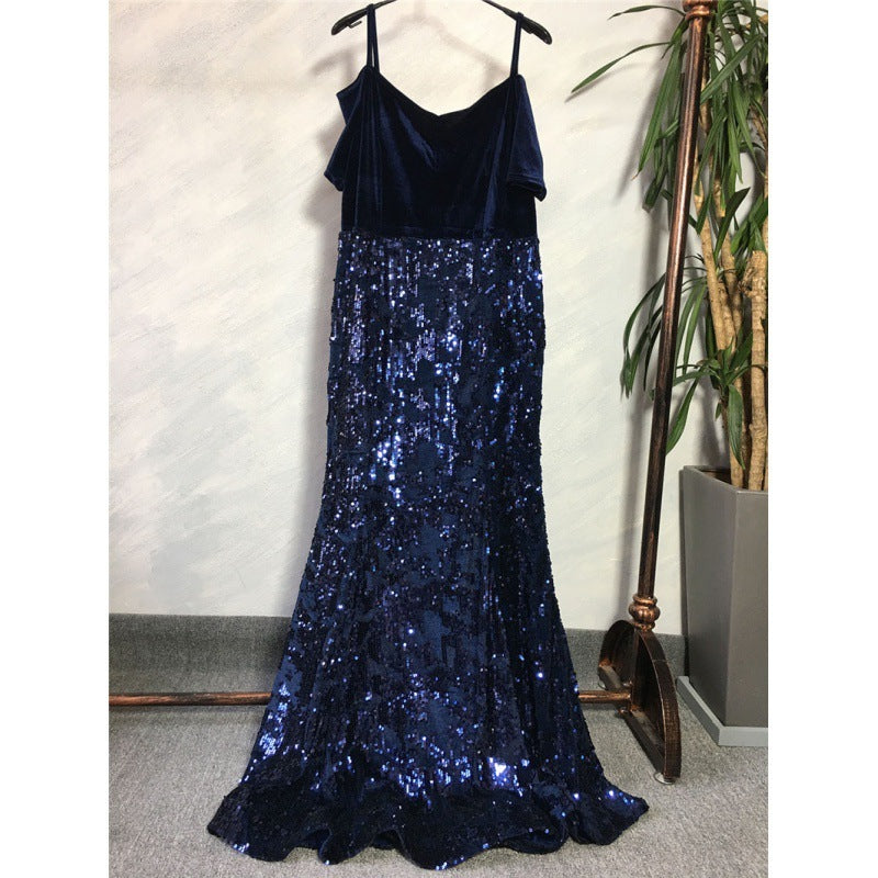 Navy blue sequin dress on a hanger against a neutral wall with a plant in the background.