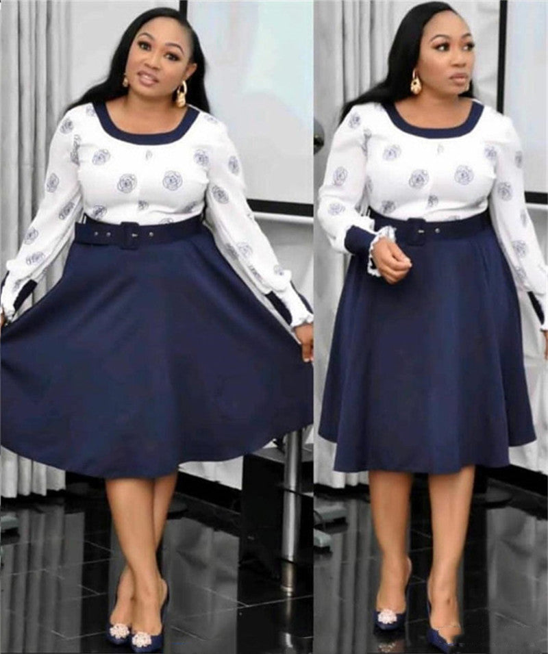 Woman wearing a white blouse with blue patterns and a navy blue skirt in an indoor setting.