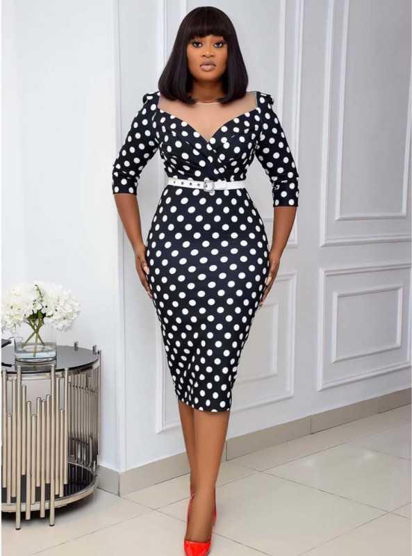 Woman wearing a black and white polka dot dress in an indoor setting.