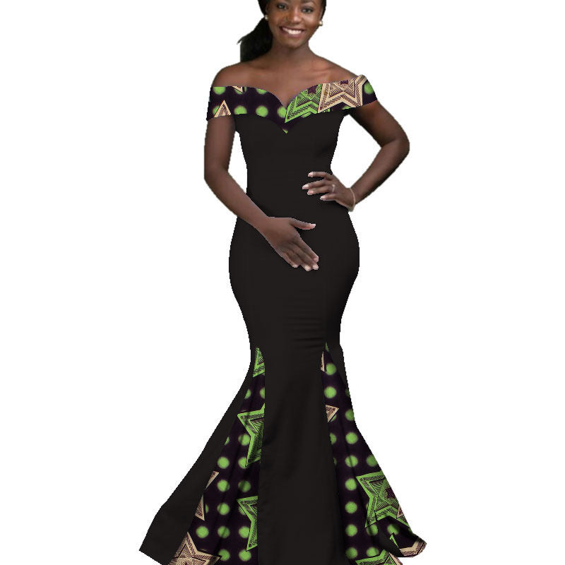 Woman wearing a black evening gown with green and gold patterns on a white background