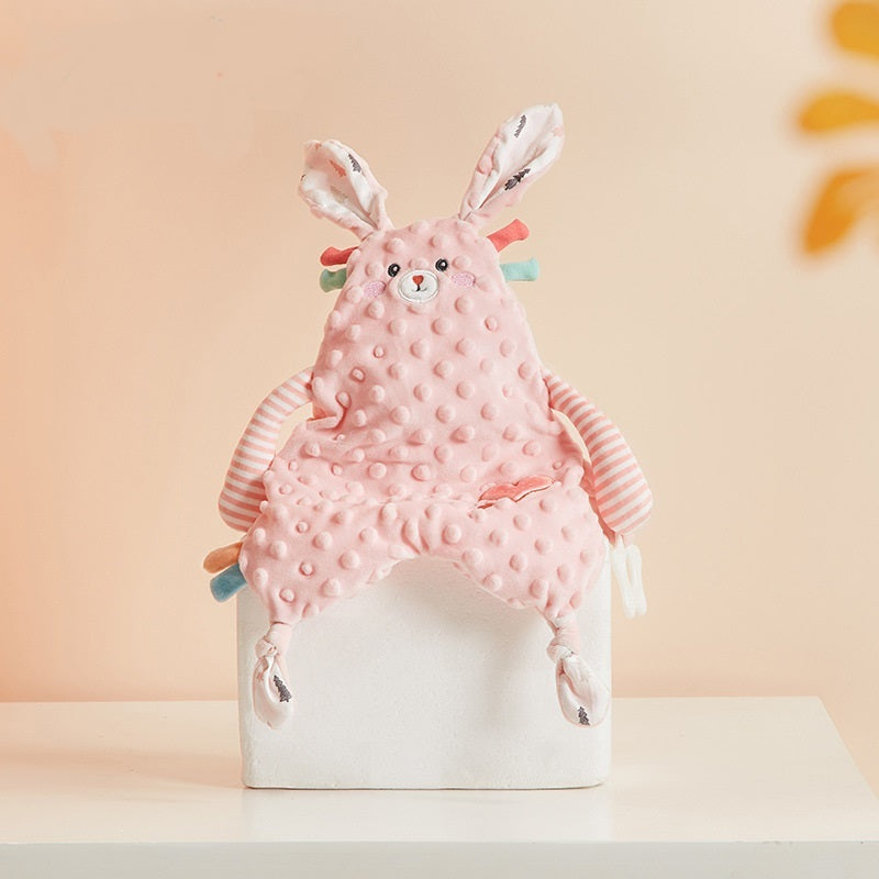 Pink plush toy with bunny ears on a white box against a beige background