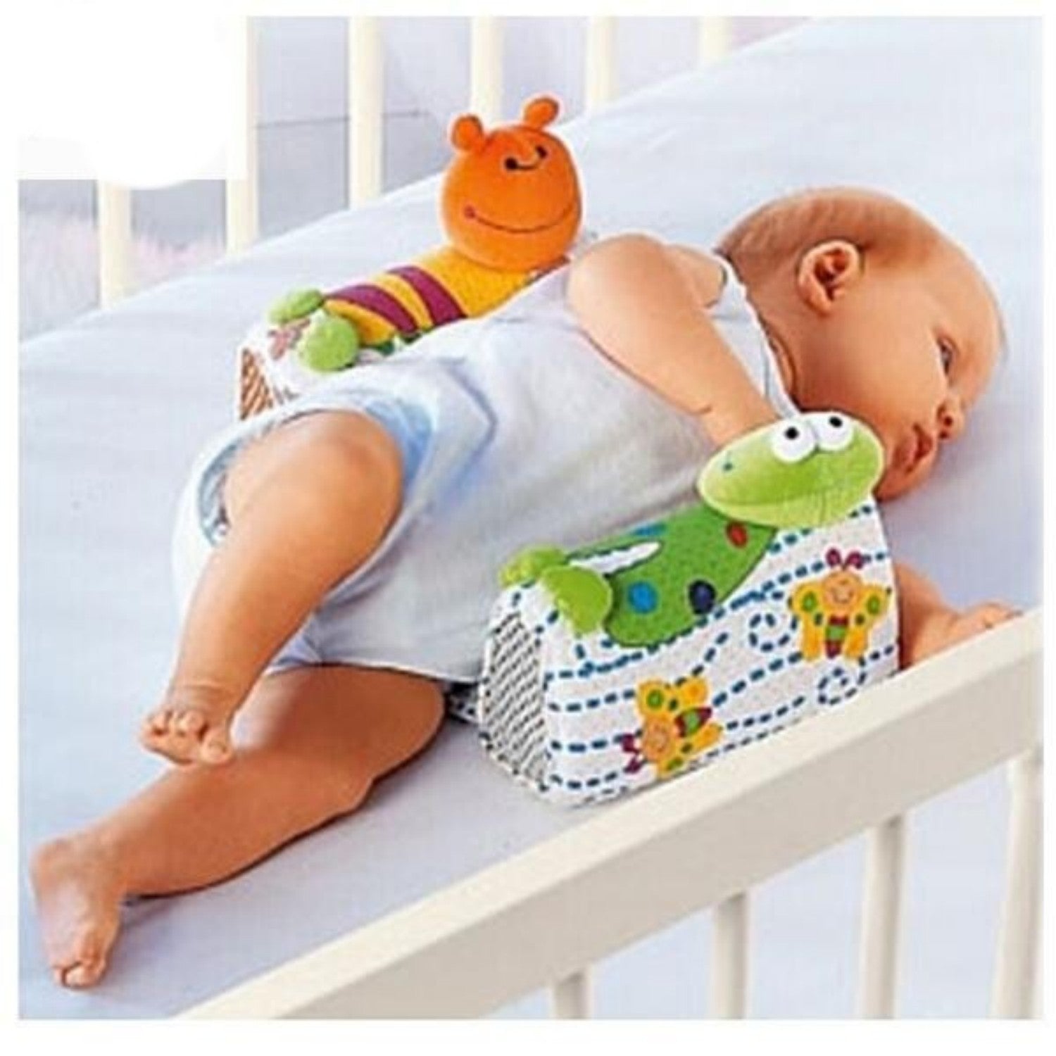 Baby sitting in a crib with a colorful toy and bib