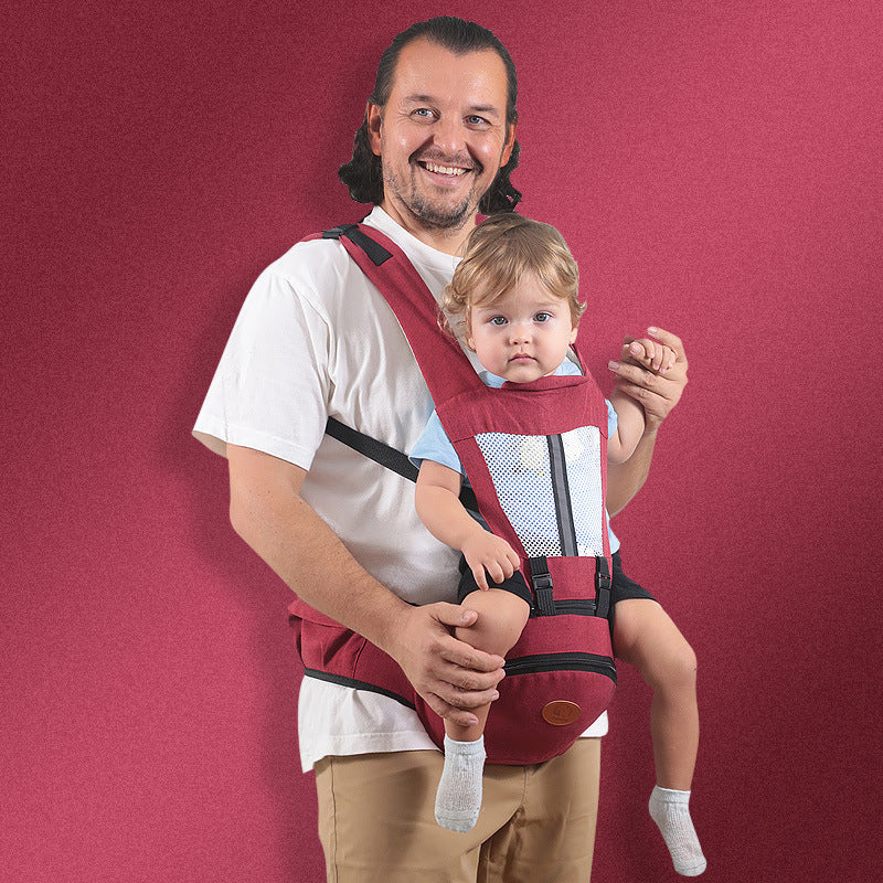 Man holding a baby in a red baby carrier against a red background