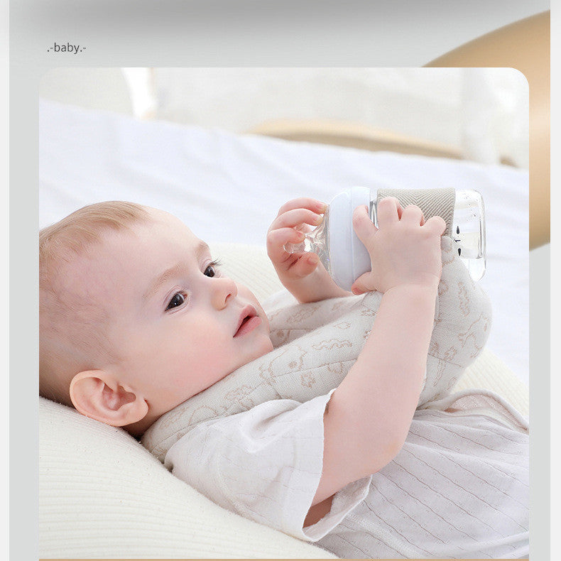Baby lying on a white pillow holding a white toy