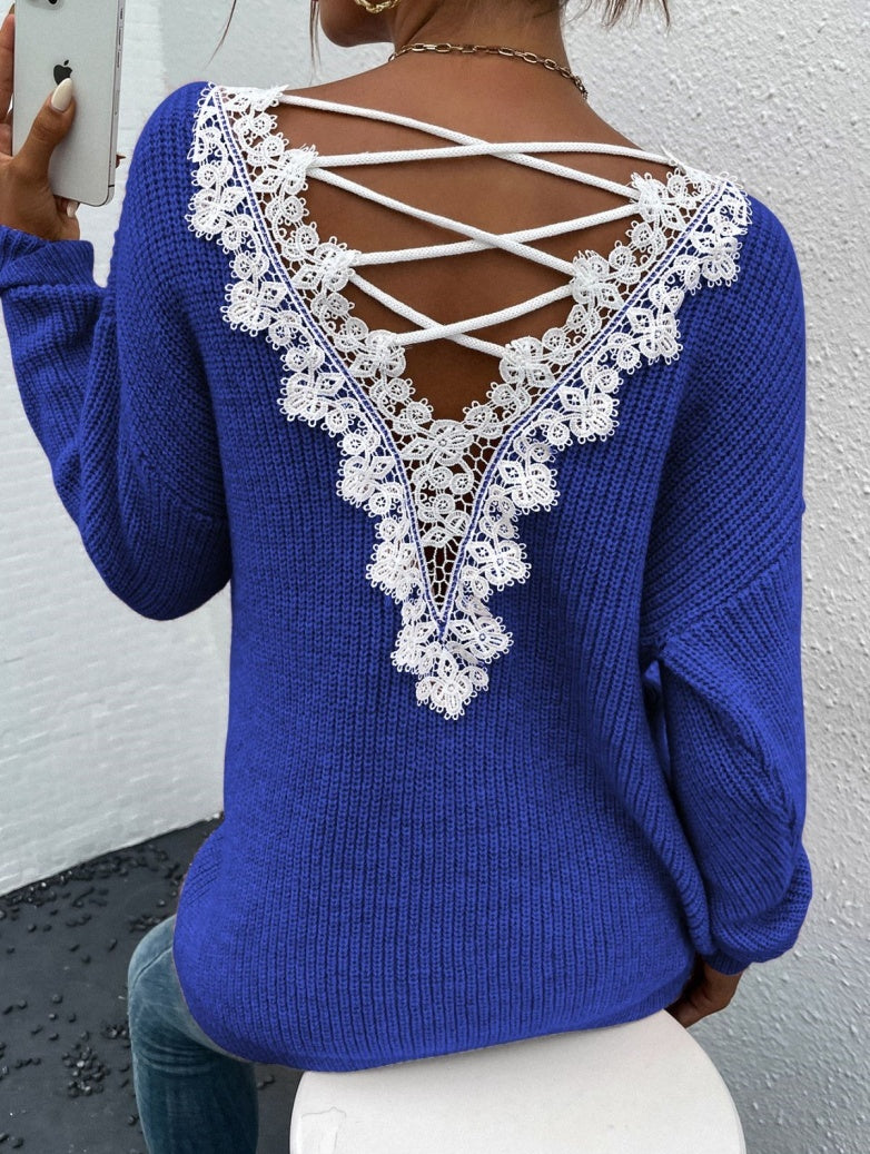 Blue sweater with lace back design against a white wall