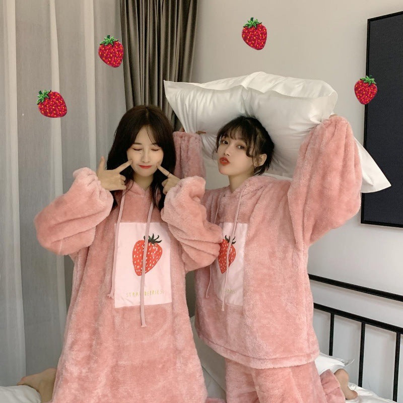 Two people wearing pink pajamas with strawberry designs in a bedroom setting.