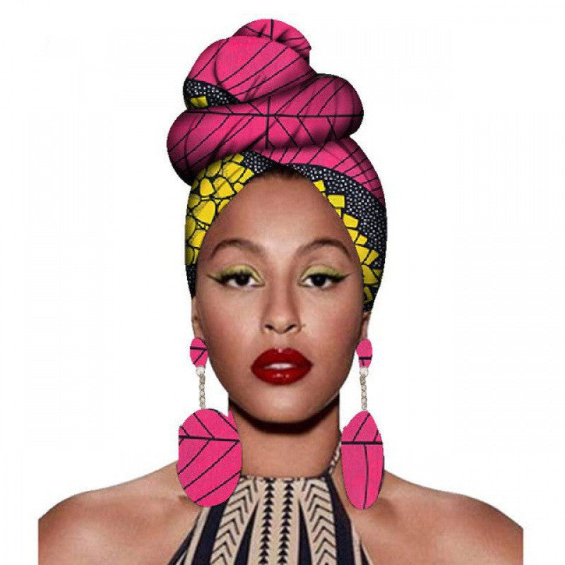 Woman wearing a colorful headwrap and earrings on a white background