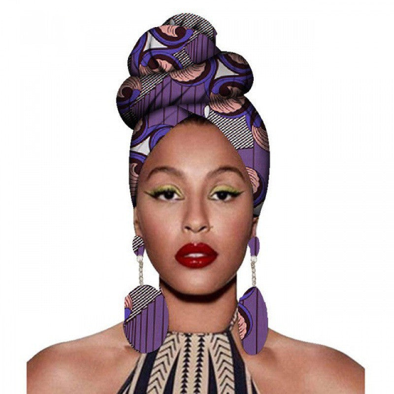 Woman wearing a purple patterned headscarf and earrings on a white background
