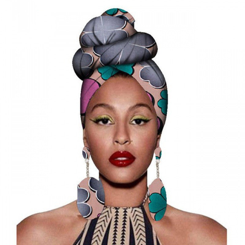 Woman wearing a colorful patterned headscarf and earrings on a white background