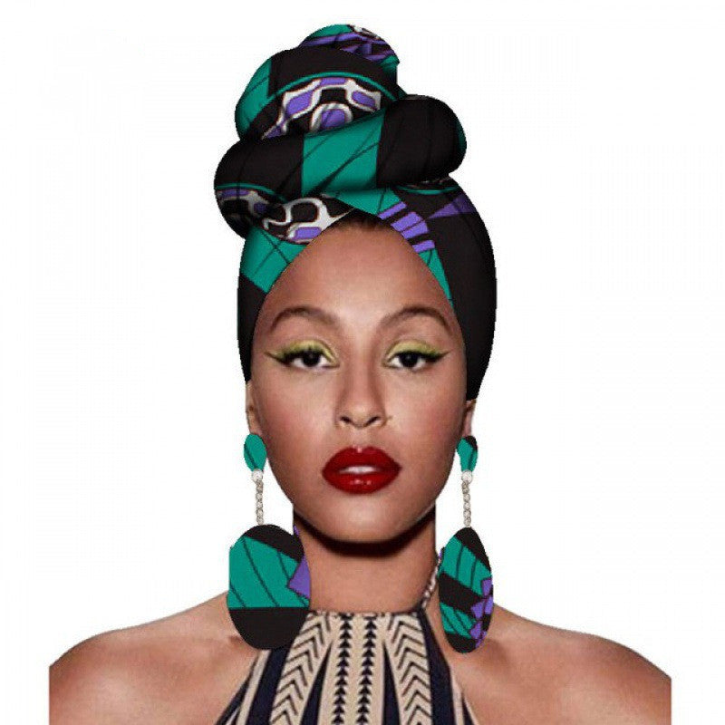 Woman wearing a colorful headwrap and earrings on a white background