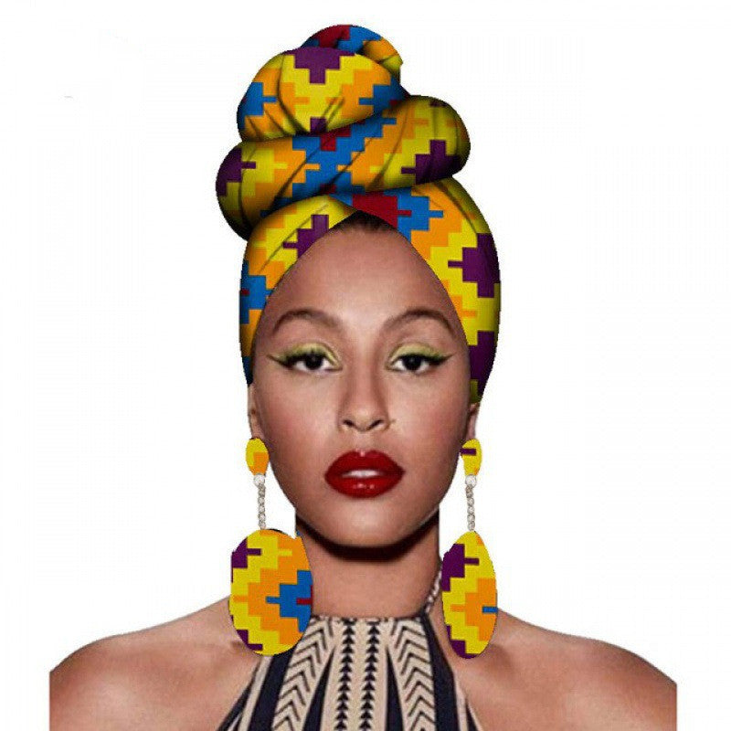 Woman wearing a colorful headwrap and earrings on a white background
