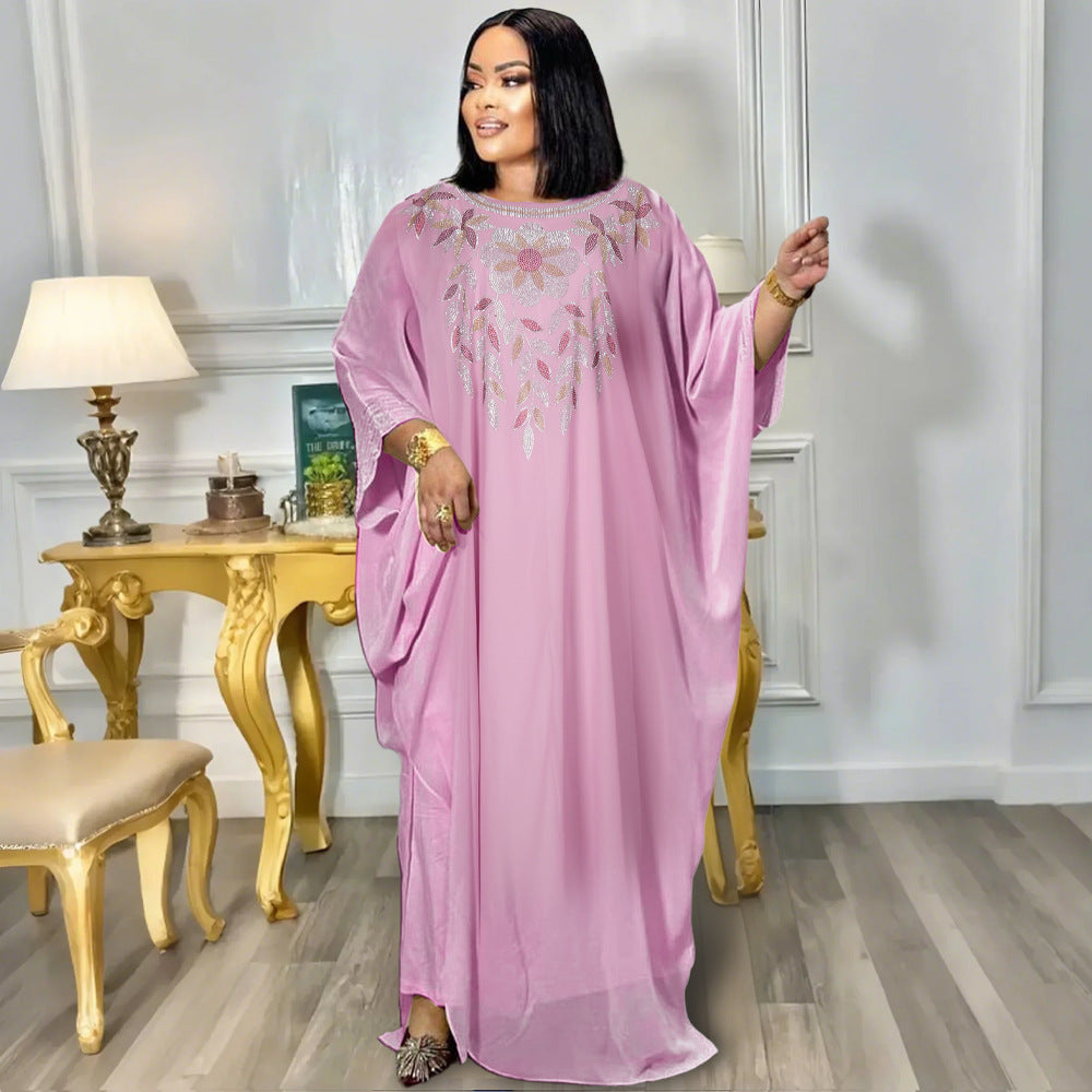 Woman in a pink dress standing in a room with a gold table and chairs.