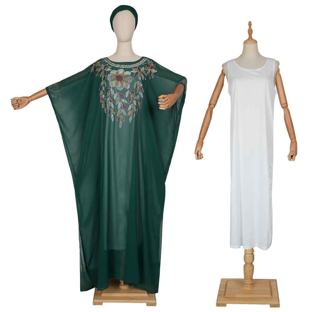 Green embroidered dress on a mannequin and white dress on another mannequin against a white background