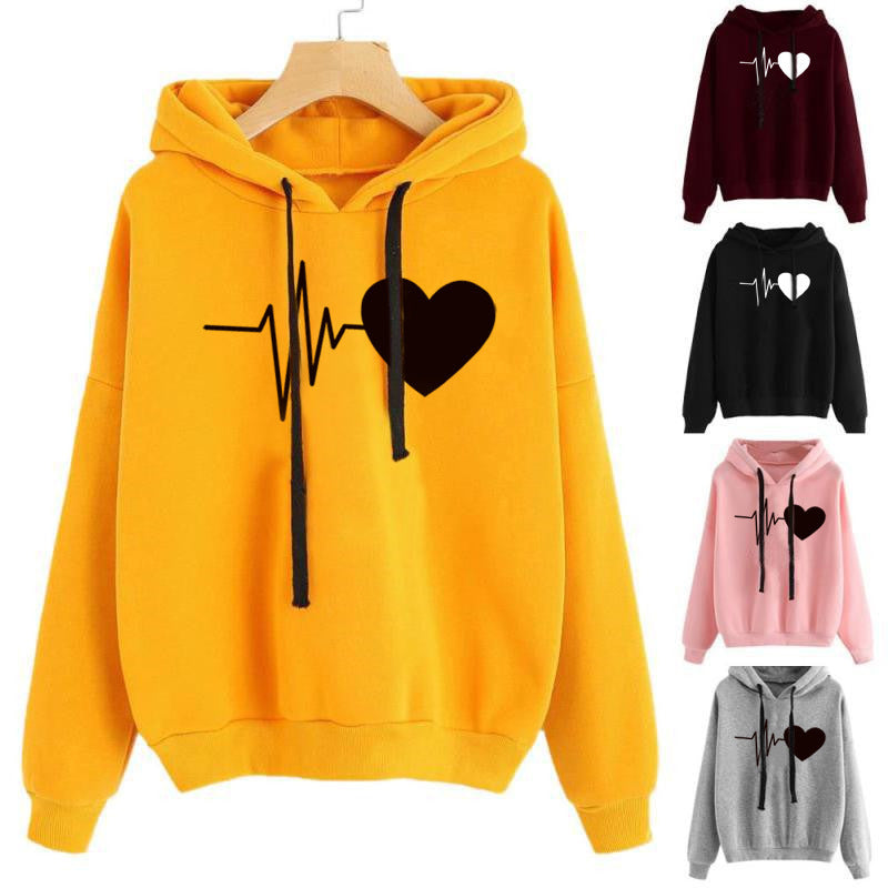 Yellow hoodie with heart and line design on a hanger, surrounded by other color variations.