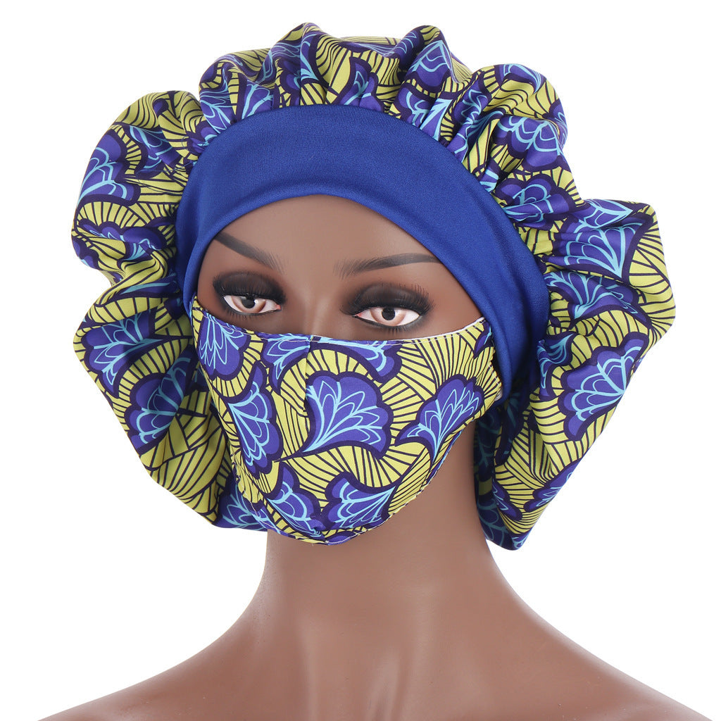 Mannequin head wearing a blue and yellow patterned headscarf and face mask on a white background