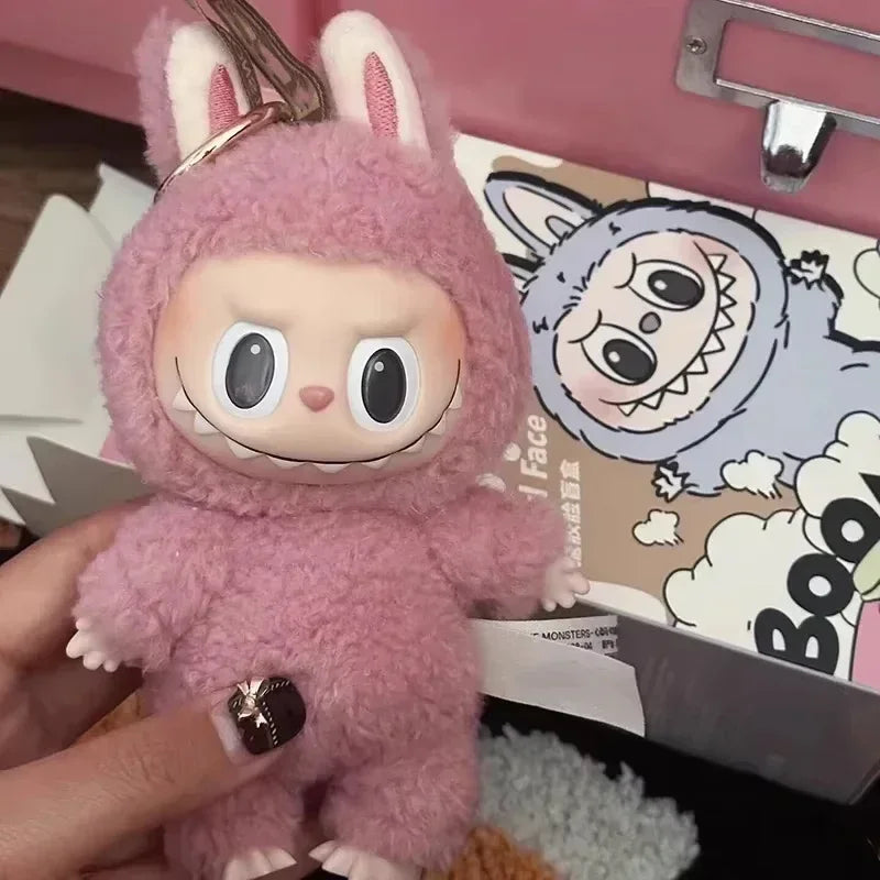 Pink plush toy with bunny ears held by a hand, with a colorful box in the background.