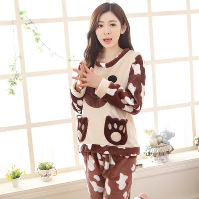 Woman wearing a brown and white animal-themed pajama set in a room with a window and plants.