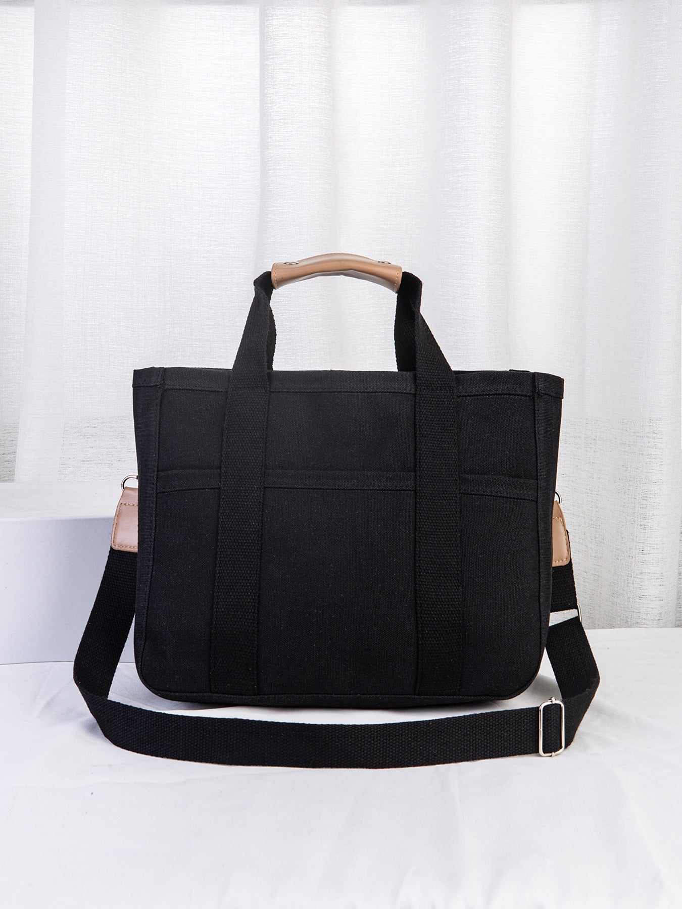 Black tote bag with a wooden handle on a white background