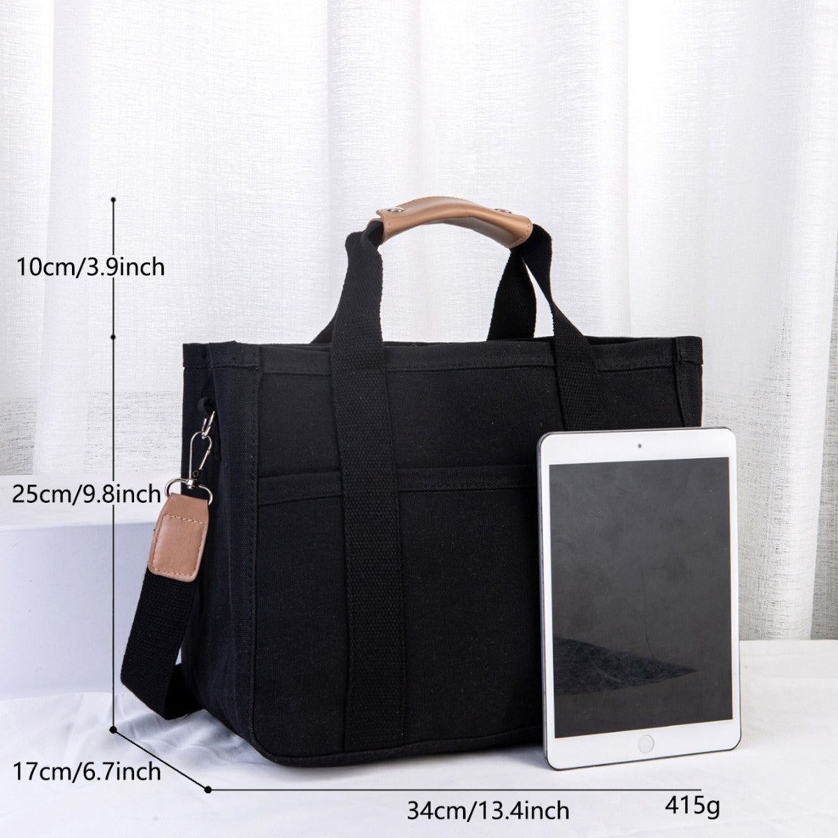 Black tote bag with measurements and an iPad for scale on a white background