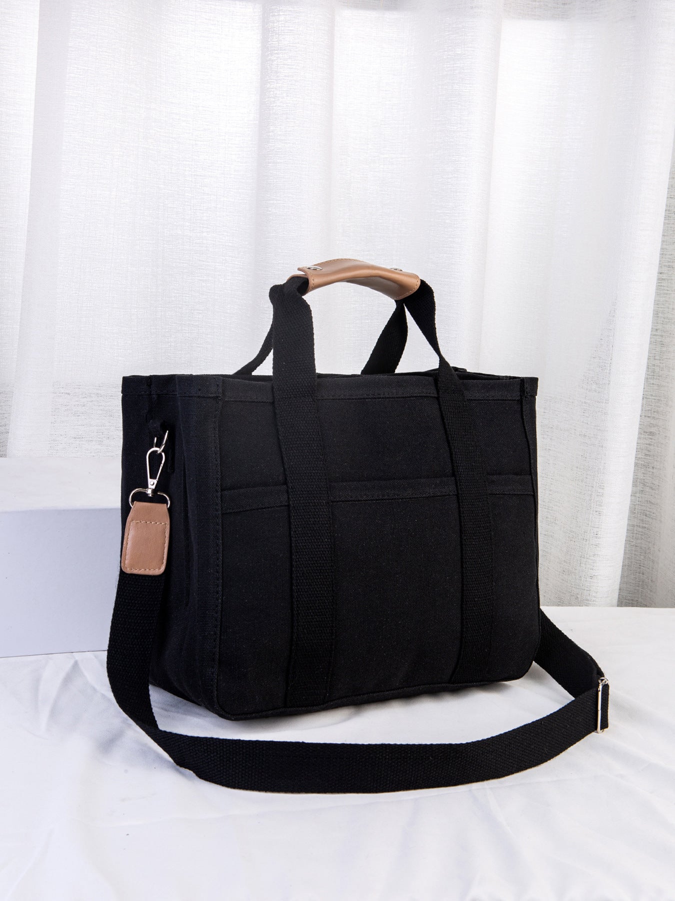 Black tote bag with a strap on a white background