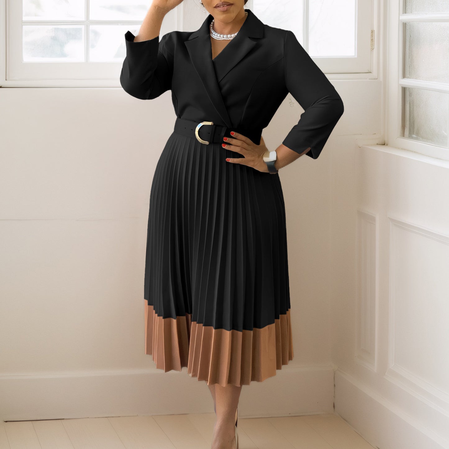 Woman wearing a black and brown dress with a belt in a room with white walls and a window.