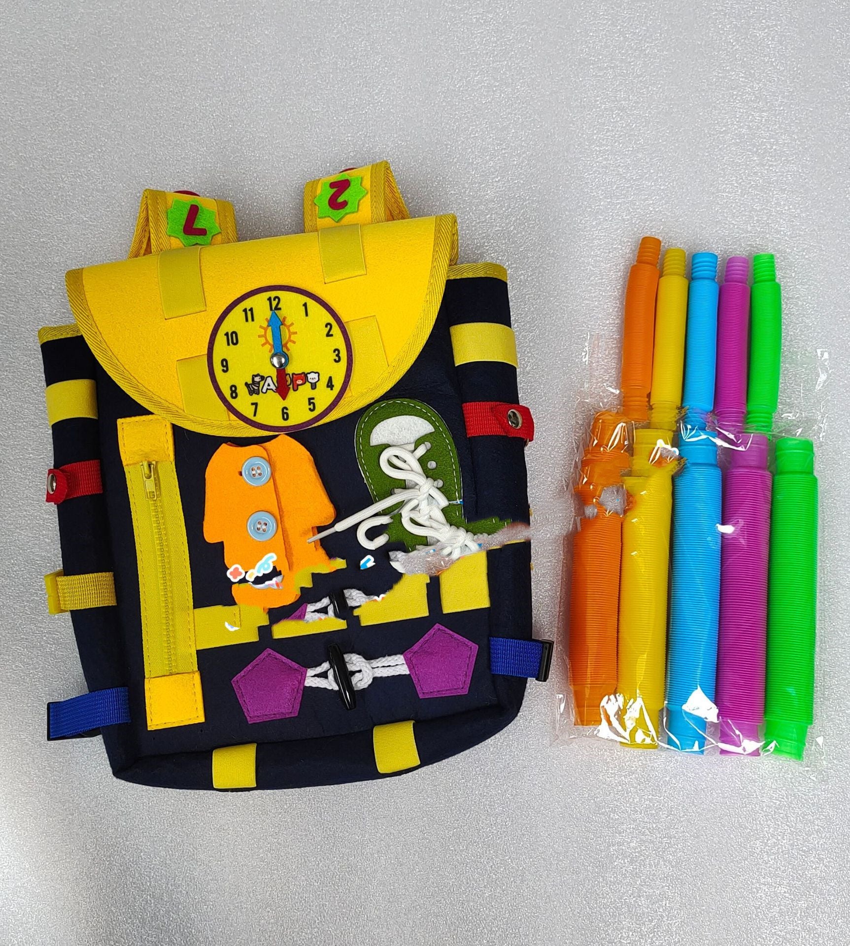 Colorful children's backpack with clock design and packages of colorful straws on a gray background