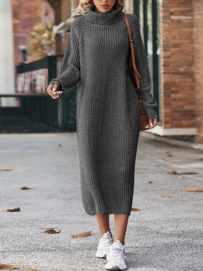 Woman wearing a long gray ribbed sweater dress with white sneakers on a street.