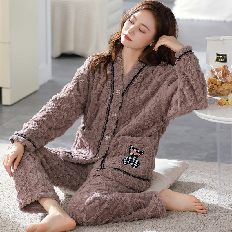Woman wearing a brown flannel pajama set sitting on a rug.