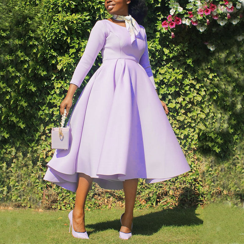 Woman in a light purple dress standing in front of green foliage
