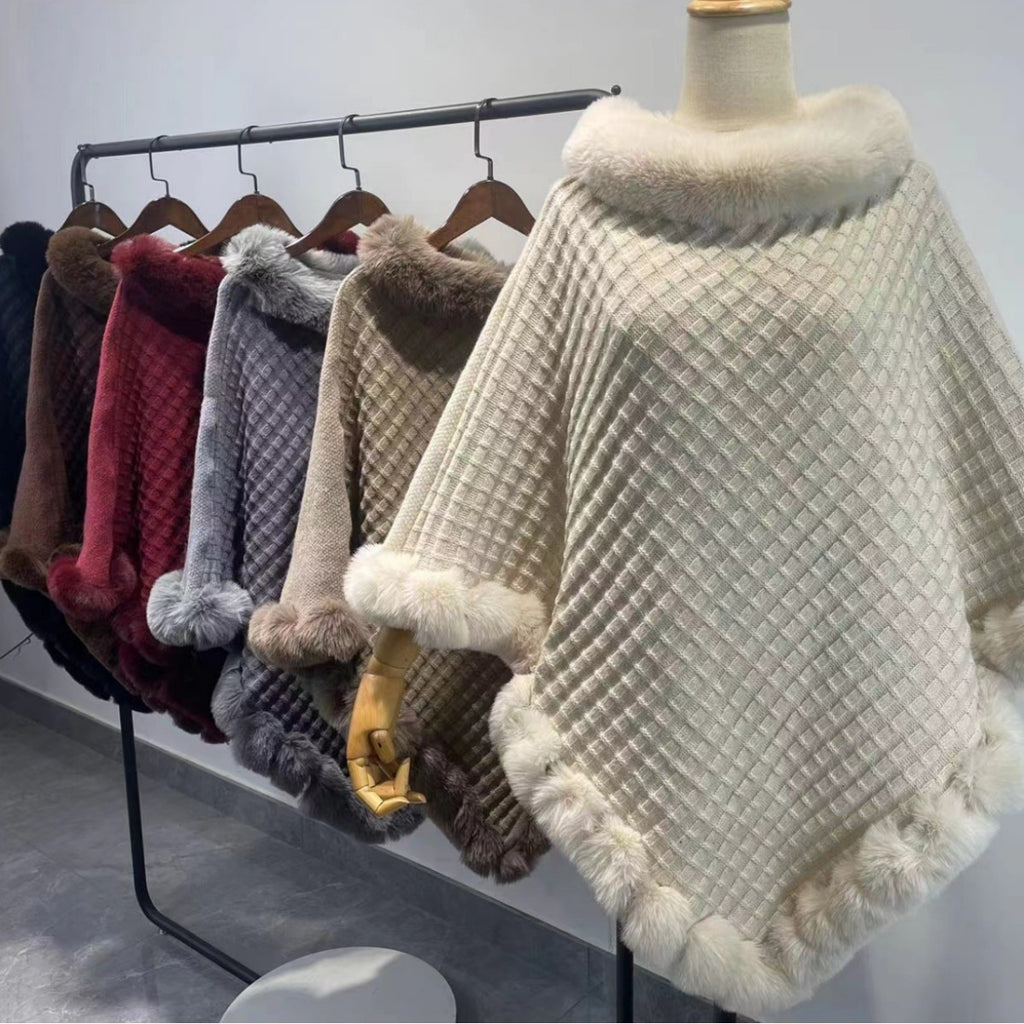 Mannequin wearing a textured poncho with a rack of similar items in the background.