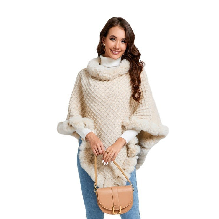 Woman wearing a beige knitted poncho with fur trim on a white background