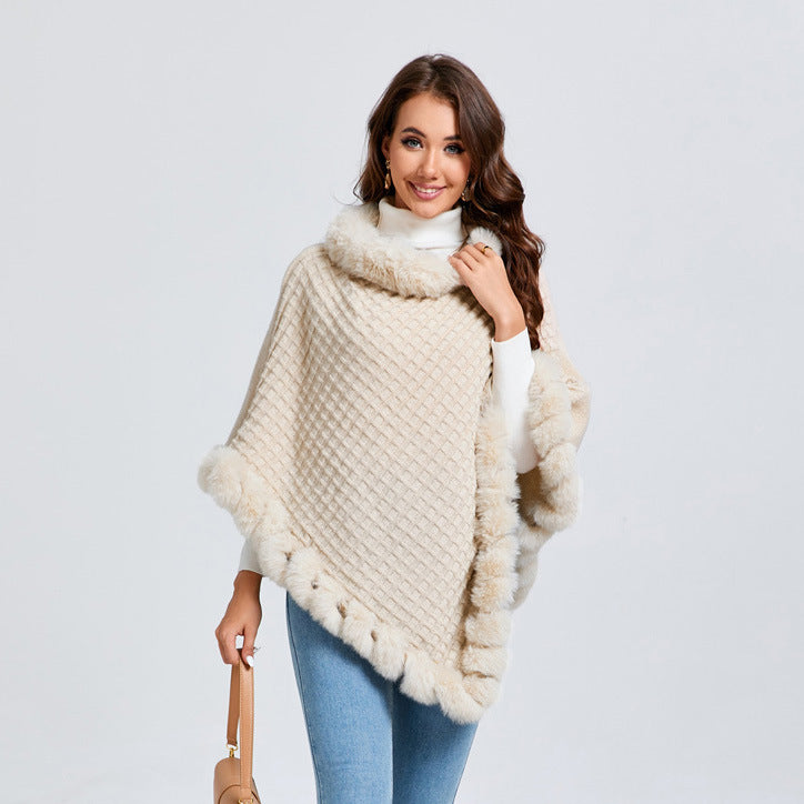 Woman wearing a beige knitted poncho with fur trim on a light gray background