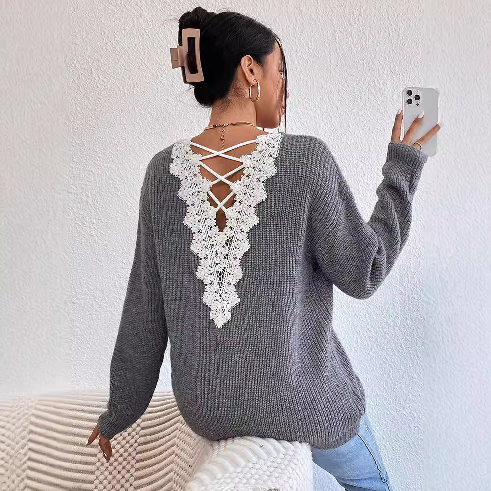 Woman wearing a gray sweater with lace detailing, taking a selfie against a white wall.