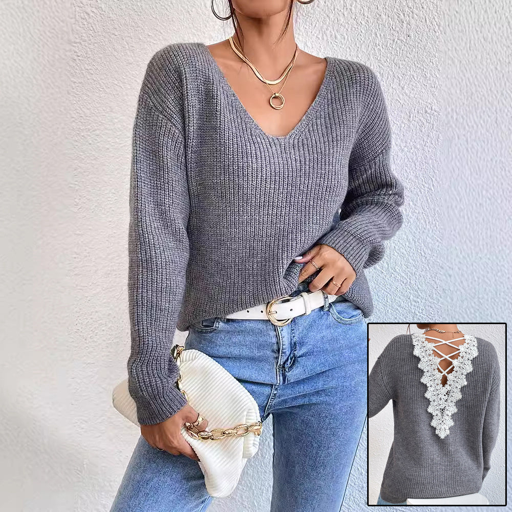 Woman wearing a gray sweater with lace detailing, holding a white clutch against a light background.