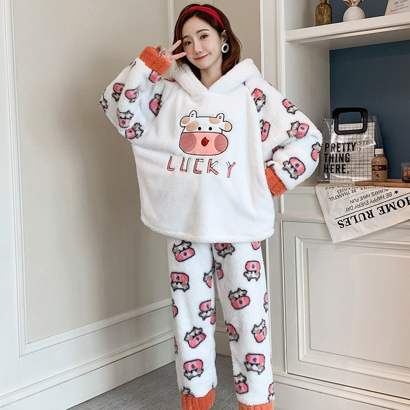 Person wearing a white fleece pajama set with cartoon cow design in a room.