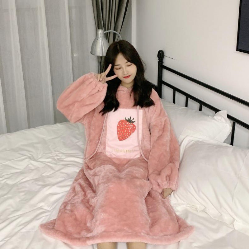 Person wearing a pink fleece outfit with a strawberry design on a bed.