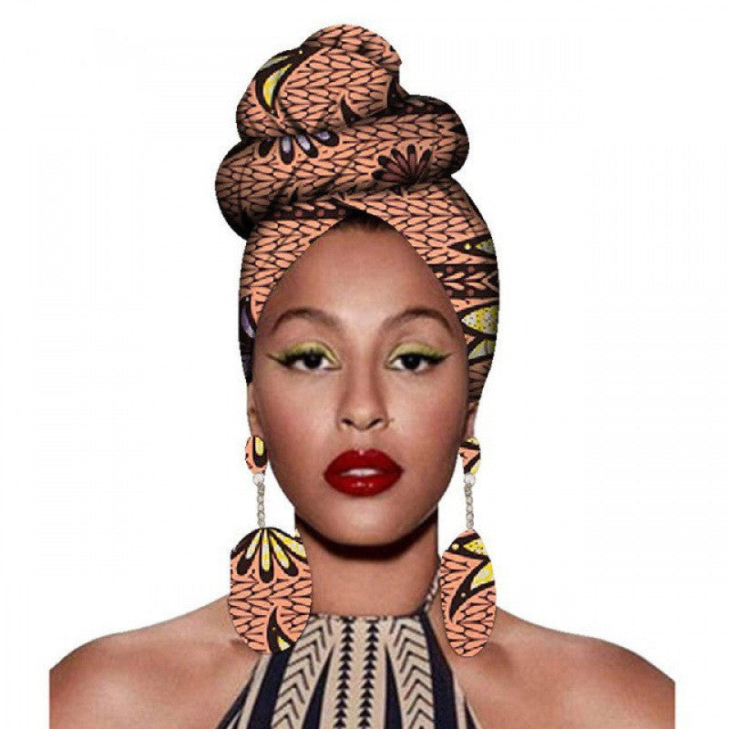 Woman wearing an African print headscarf and earrings on a white background