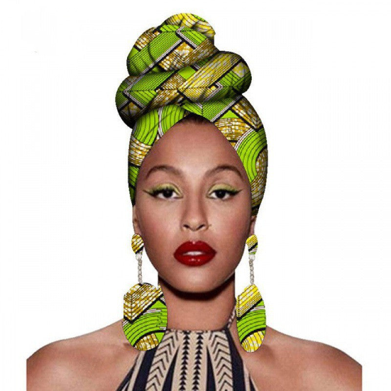 Woman wearing a green and yellow patterned headscarf and earrings on a white background