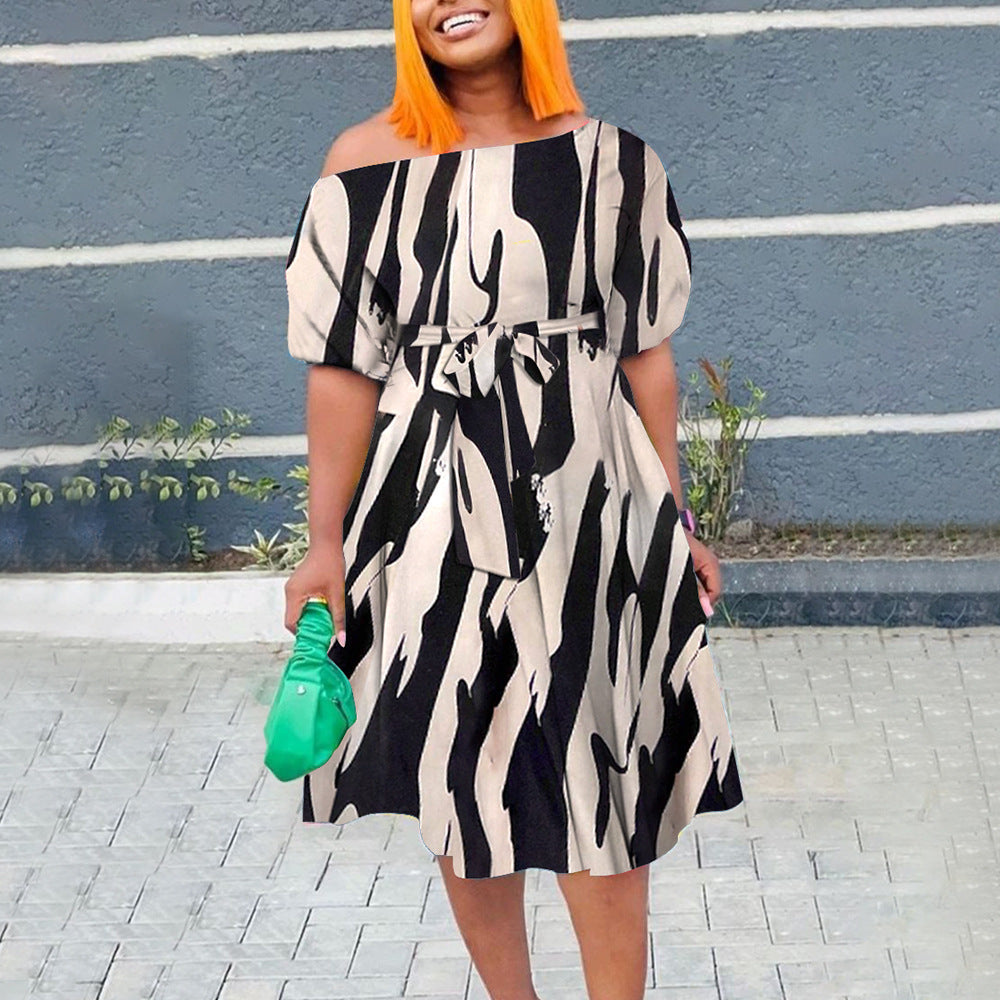 Woman wearing a black and white patterned dress with orange hair against a blue wall.