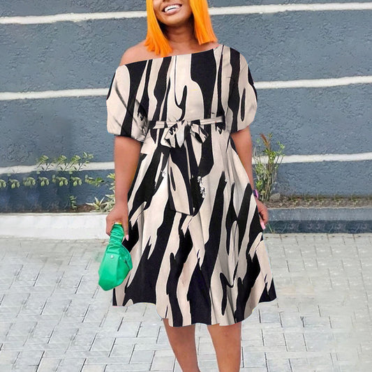 Woman wearing a black and white patterned dress with orange hair against a blue wall.